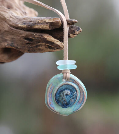 Anhänger Welle aus Keramik mit Perlen aus Strandscherben an einem veganen Lederband in Wildleder - Optik.